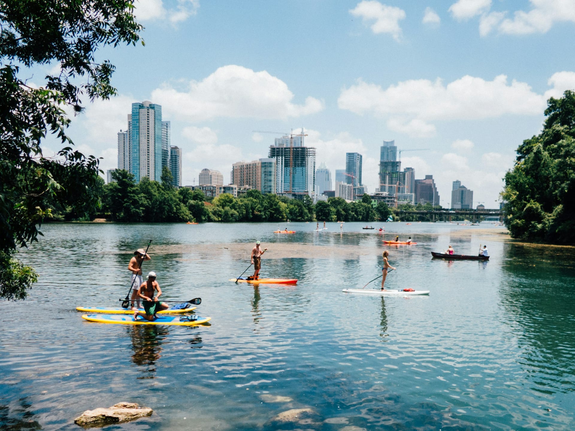 Paddle boarders on Lady Bird Lake in front of the Austin skyline